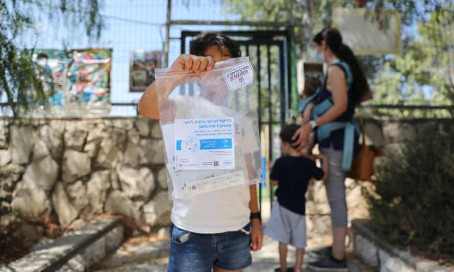 A girl in Jerusalem holds up a Covid test kit amid a nationwide testing campaign before Israeli schools open.