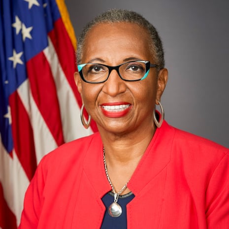 a woman smiles in front of an American flag