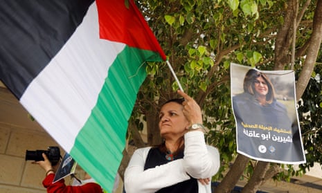 A woman holds a Palestinian flag next to a picture of Shireen Abu Aqleh in the Israeli-occupied West Bank