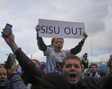 Coventry fans, including one boy holding a ‘Sisu out’ banner, demonstrate before a League One fixture against Rochdale
