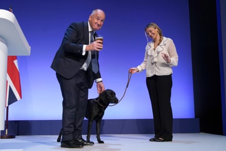 Kevin Hollinrake stands with a pint of beer next to woman with black labrador