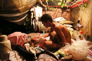 Manila, PhilippinesA man who lives with his family in a tent erected atop a tombstone, feeds his two-month old twins at the North Cemetery