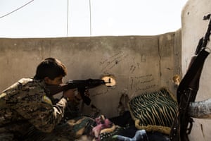 An SDF fighter checks for enemy movements from a sniper position overlooking Isis-held areas.