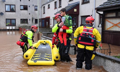 Coastguard rescue workers evacuate a family trapped at home in a flooded street in Brechin.