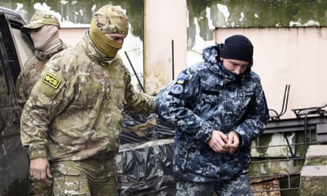 A Ukrainian sailor is escorted by a Russian intelligence officer to a court room in Simferopol, Crimea, on Tuesday.