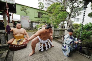 Four sumo wrestlers pose in a Japanese garden