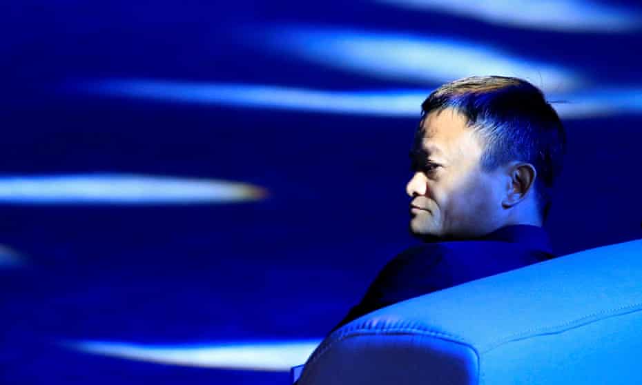 Jack Ma photographed in profile siting on a settee, his face partially illuminated by rays of pale blue light