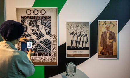 A woman takes a picture of Olympic Games posters displayed at the exhibition The Olympic Games, a mirror of society
