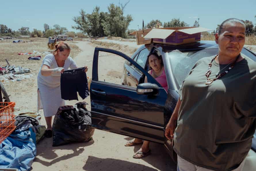 Three women near a car, one woman holding shorts
