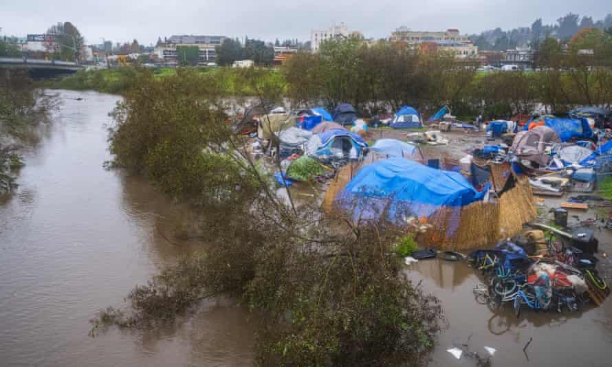 Tents surrounded by brown flood water and a smattering of trees