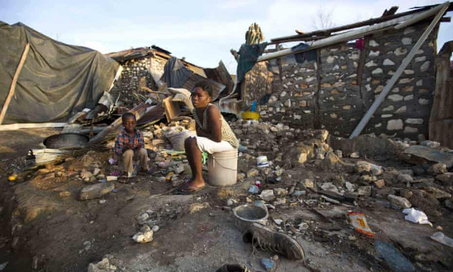 A woman and a child sit on buckets amid the ruins of their home destroyed by Hurricane Matthew, in Jeremie, Haiti, on Monday.