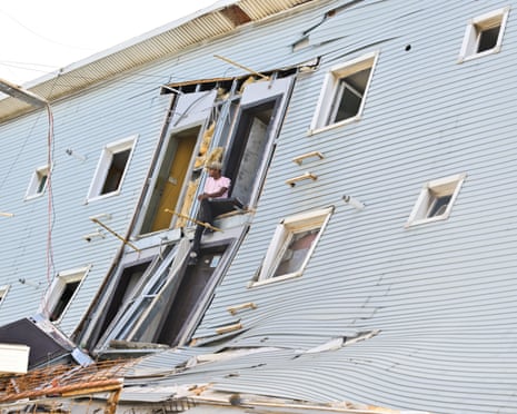 A man sitting in the collapsed doorway of a damaged building.