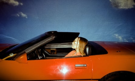 A woman with long hair sits in a red sports car