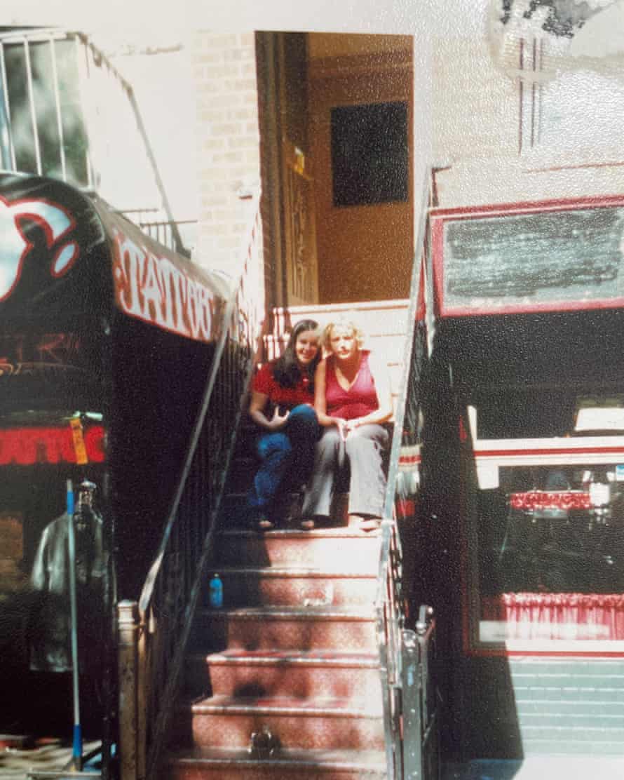 Two women sit together on outdoor steps leading up from street-level to a doorway