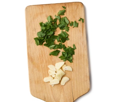 A chopping board with chopped parsley and garlic