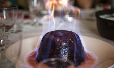 Un pudding de Noël en flammes sur une table de dîner.