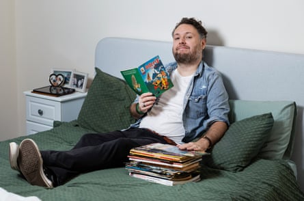 The writer lying on his bed with a pile of comics beside him
