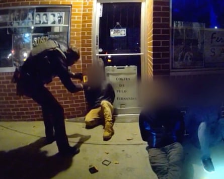 A still from bodycam footage shows a federal agent using a facial recognition app while a person, whose face has been blurred, sits on ground