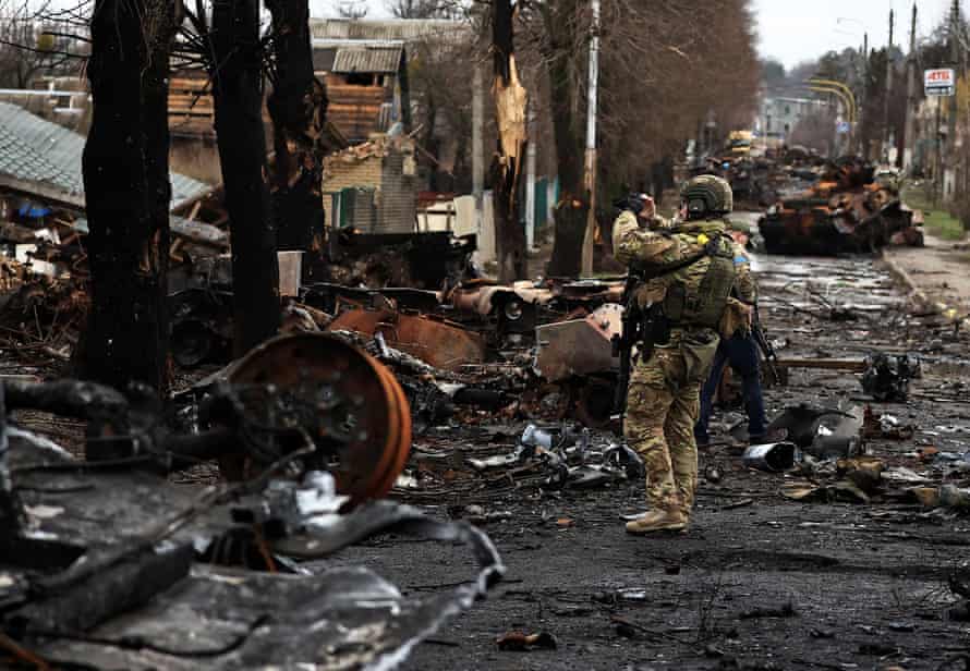A serviceman films a destroyed Russian tank and armoured vehicles in Bucha.