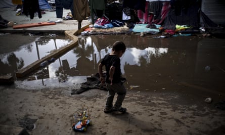 A Honduran boy plays next to the flooded area at a migrant shelter in Tijuana, Mexico.