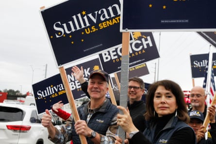 people hold navy, white and yellow signs outside saying ‘Sullivan US Senate’