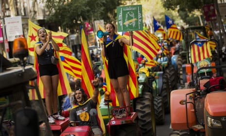 People with the Catalan independence flag on top of parked tractors during a protest by farmers in Barcelona.