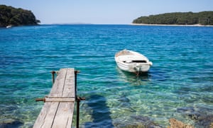 Bateau de mer bleu cristal et jetée à Cikat Bay, Losinj