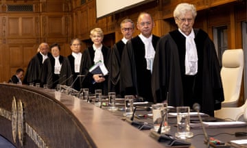 A line of judges walk to their seats in a courtroom
