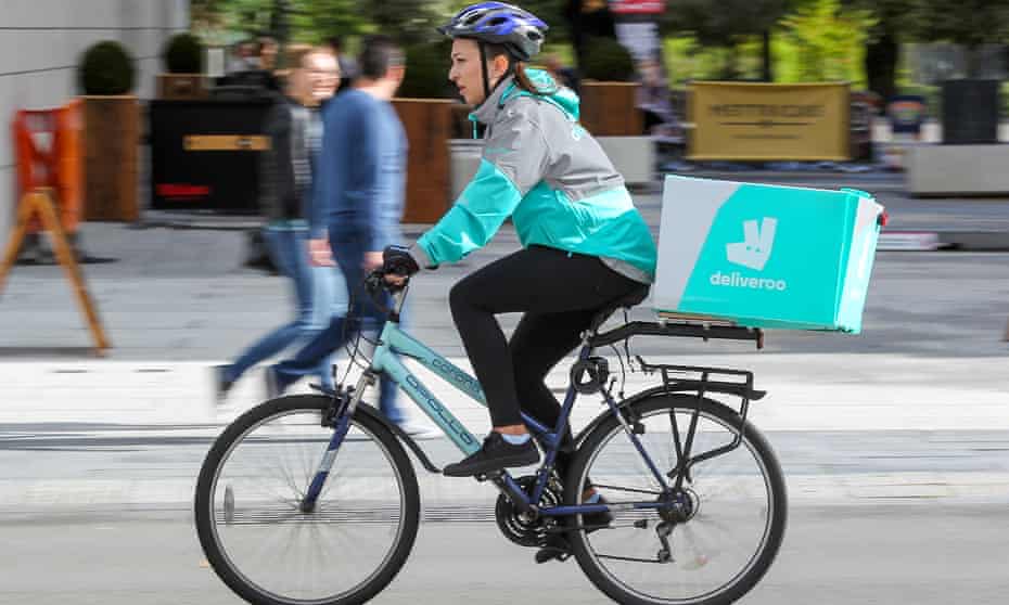 A female Deliveroo cyclist riding with a package on her bike