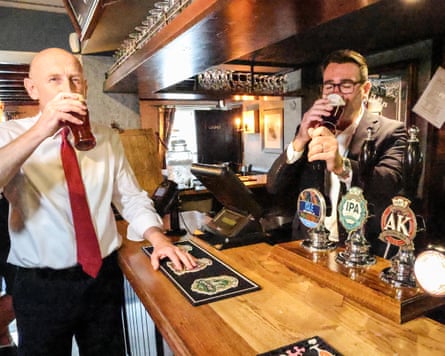 Burnham and Healey stand either side of the bar drinking a pint