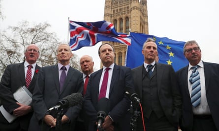 Anti-Brexit protesters hold flags as Nigel Dodds speaks outside parliament, flanked by other DUP MPs.