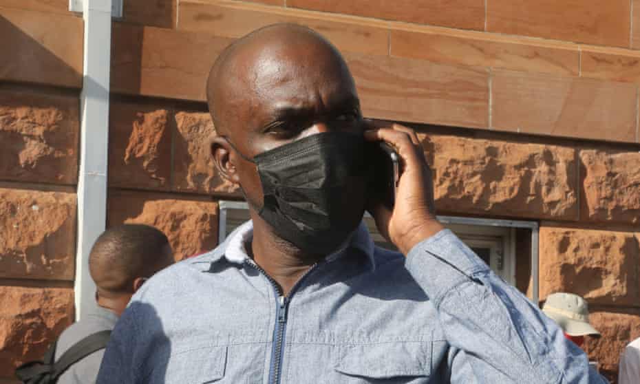Jeffrey Moyo wearing mask speaking on mobile phone outside court.