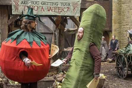 Mathew Baynton and Jim Howick, dressed as a tomato and cucumber, hold flyers in a village street