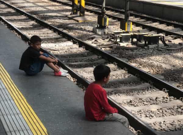 Deux jeunes garçons sont assis au bord d'un quai de gare