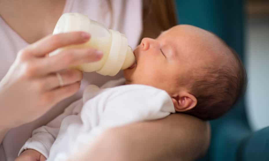 A close up of a newborn baby being fed with a bottle. 