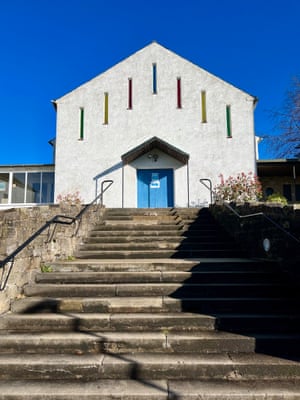 a modest looking church with seven narrow windows and a blue door at the top of a steep series of steps