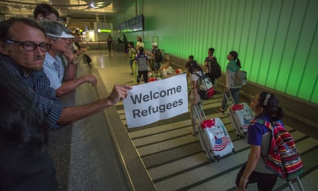A man displays a welcome sign near arriving travellers on the first day of the partial reinstatement of the Trump travel ban in Los Angeles on 29 June 2017.