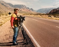 Man with video camera on side of road