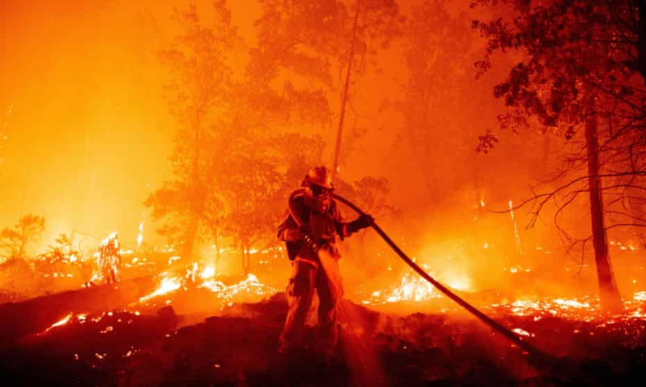 A firefighter douses flames as they push towards homes during the Creek fire in the Cascadel Woods area of unincorporated Madera County, California