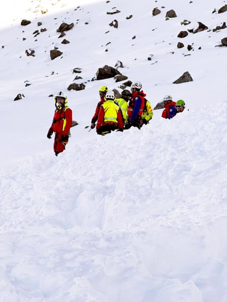Alpine rescuers in red and yellow at the scene of an avalanche in Italy