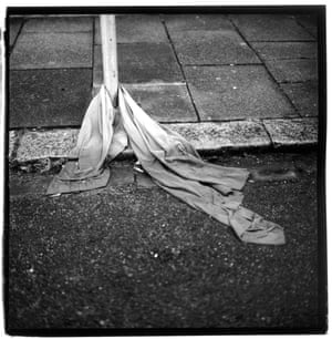 Discarded cloth wrapped around a post on a pavement, spilling onto the road