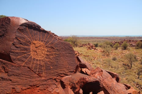 An image of a sun drawn into a rock in a dry landscape.
