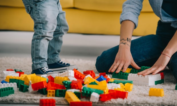 Cropped view of mother and son playing with Lego on carpet in living room