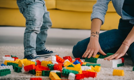 cropped view of mother and son playing with lego on carpet in living room