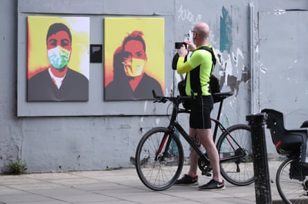 A cyclist takes a photograph of street art in Dublin created by the collective Subset.