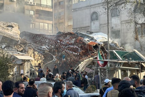 Emergency and security personnel gather at the site of strikes which hit a building next to the Iranian embassy in Syria's capital Damascus.