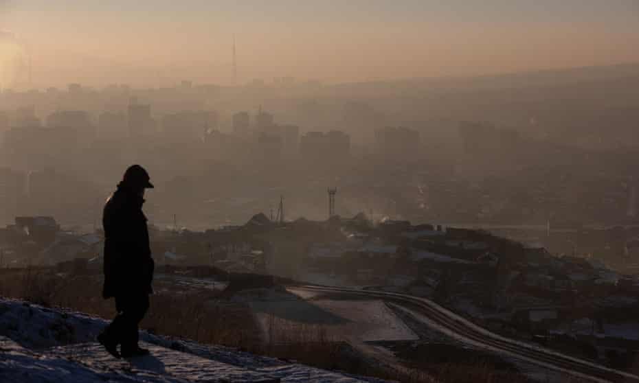man watching smoke hanging over houses on a polluted day in Ulaanbaatar