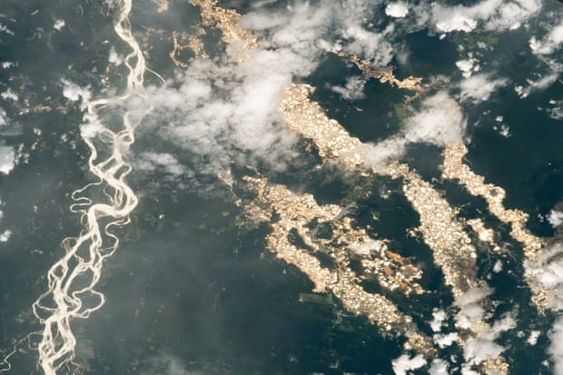 A photograph taken from the International Space Station shows numerous gold prospecting pits illuminated by reflected sunlight in Madre de Dios, eastern Peru, 24 December 2020.