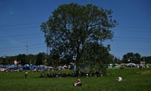 Revellers shelter under a tree at Worthy farm in Somerset during the Glastonbury music festival