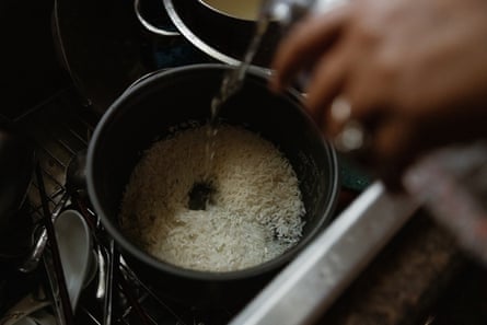 Hand pouring water into pot of white rice